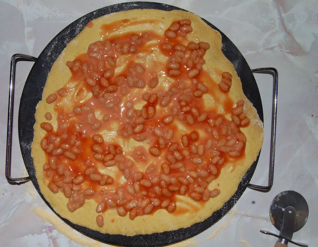 Baked bean pizza being assembled